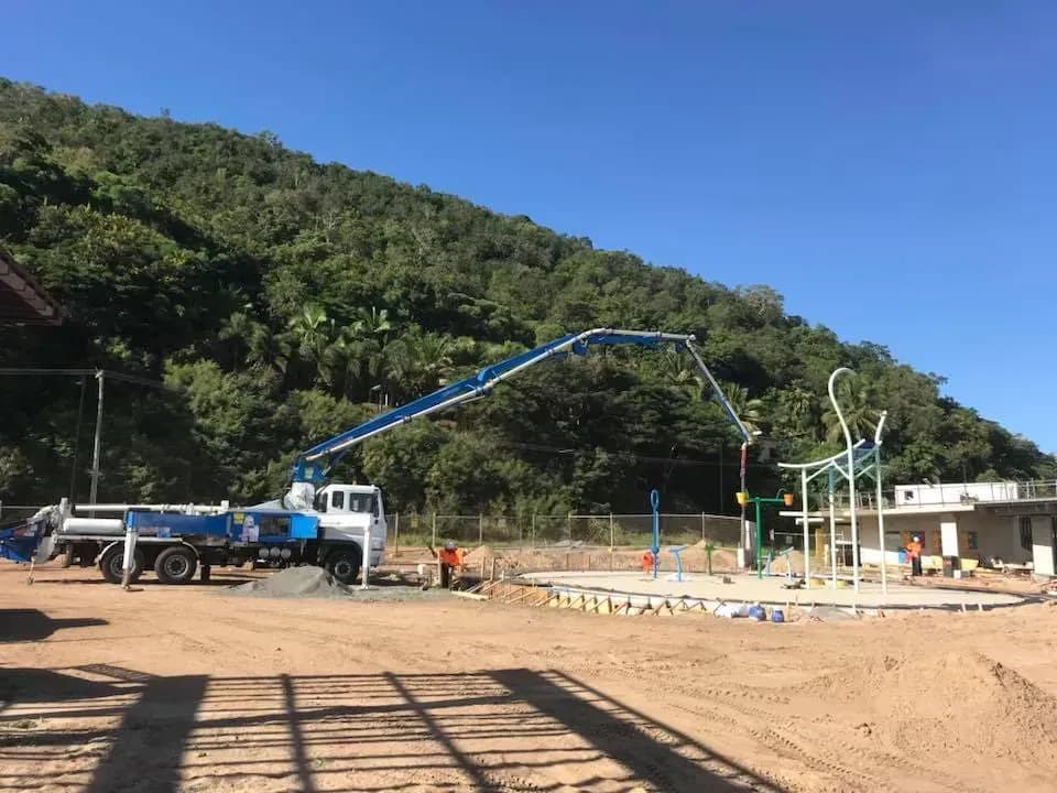 Concrete boom pump truck on a hillside construction site
